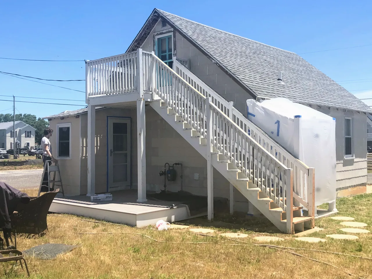 The original beach house during restoration, with exposed siding and an exterior staircase.