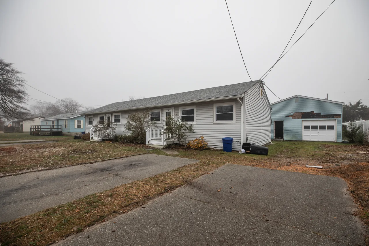Four neighboring bay cottages seen from the street, awaiting renovation.